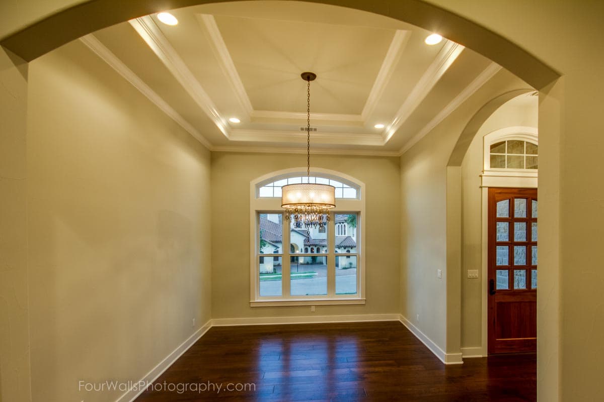 Interior view of a room with coffered ceiling, large arched window, and wood door. Architectural design.