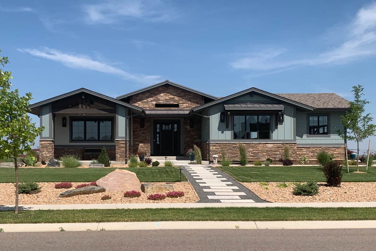 House plan exterior. One-story Craftsman home with a stone and wood facade, gabled rooflines, and a covered entry.