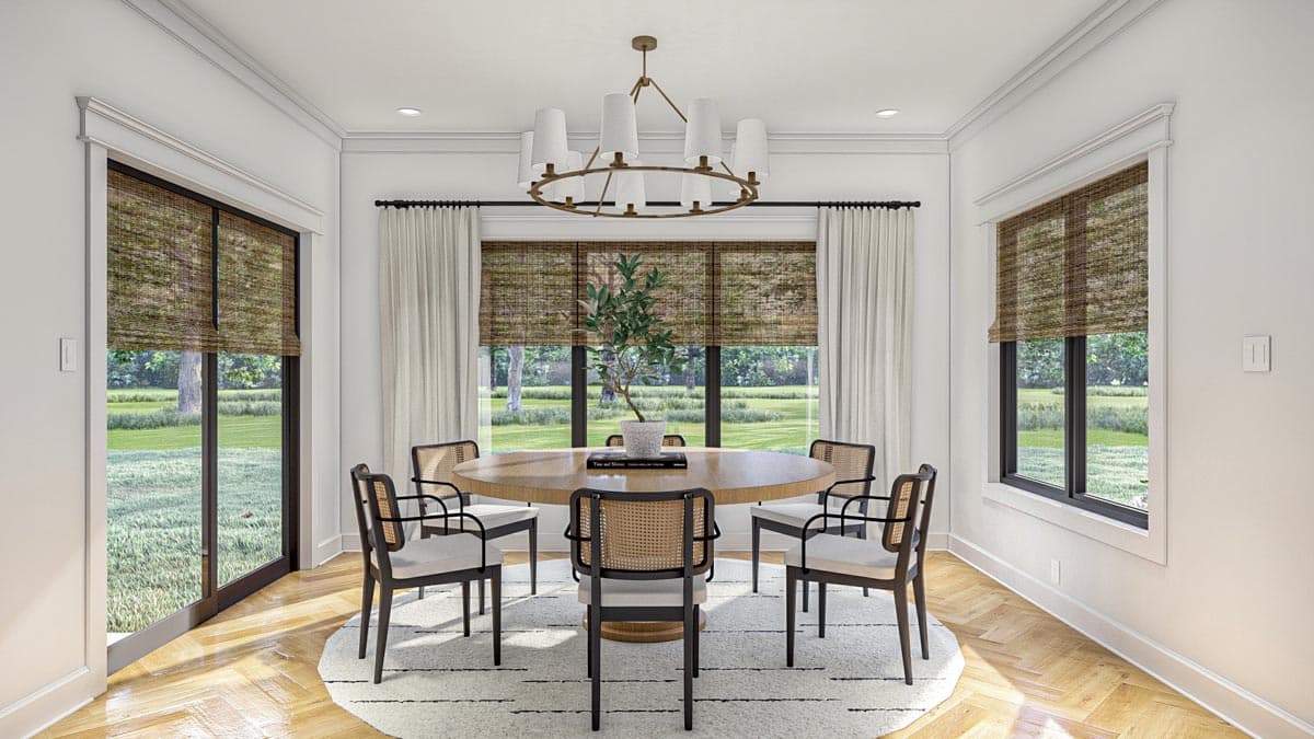 Dining room with round table, chairs, large windows, and sliding glass door. Neutral rug and chandelier.