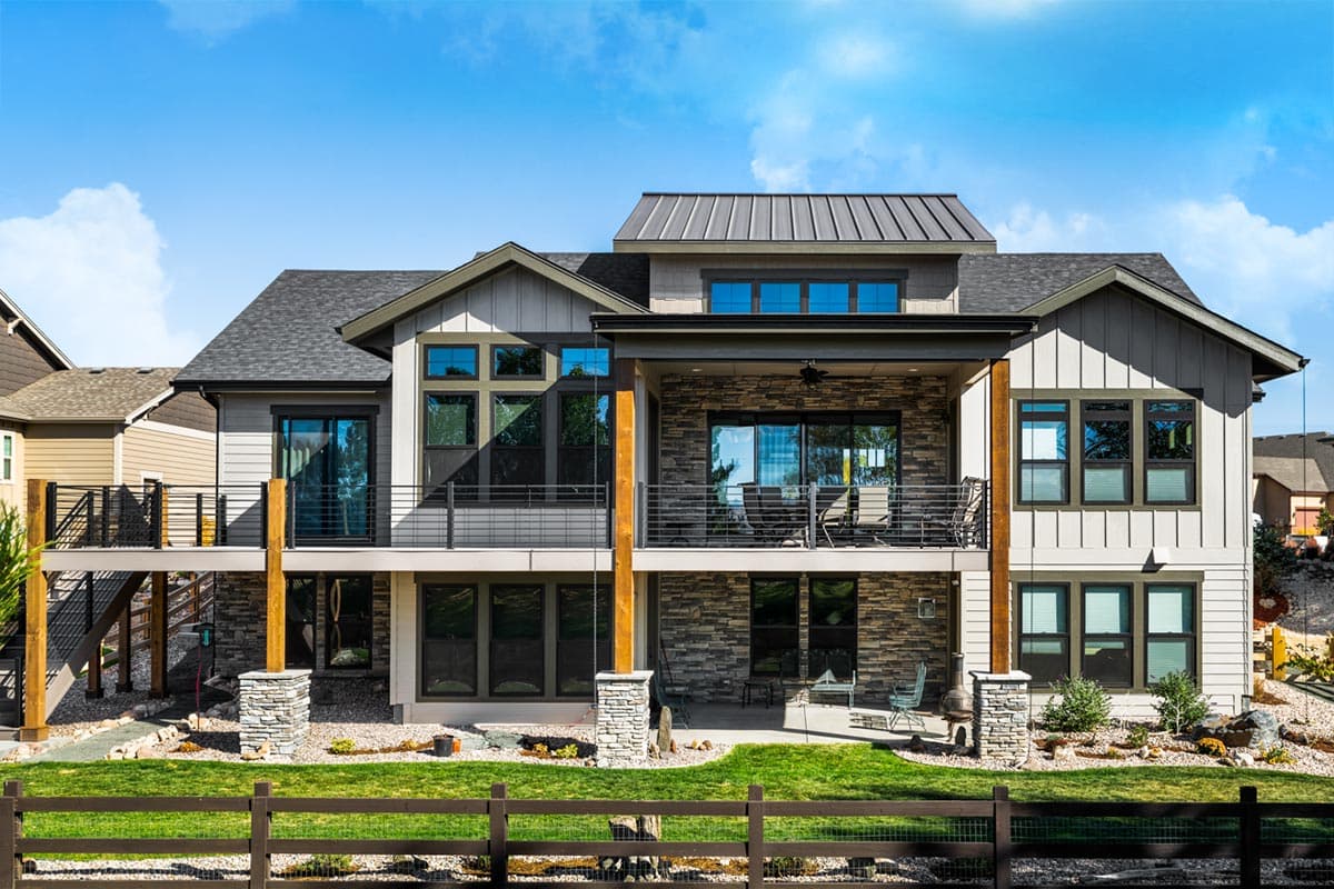 Modern house plan exterior with stone and vertical siding, multiple gables, and two-story covered patio.