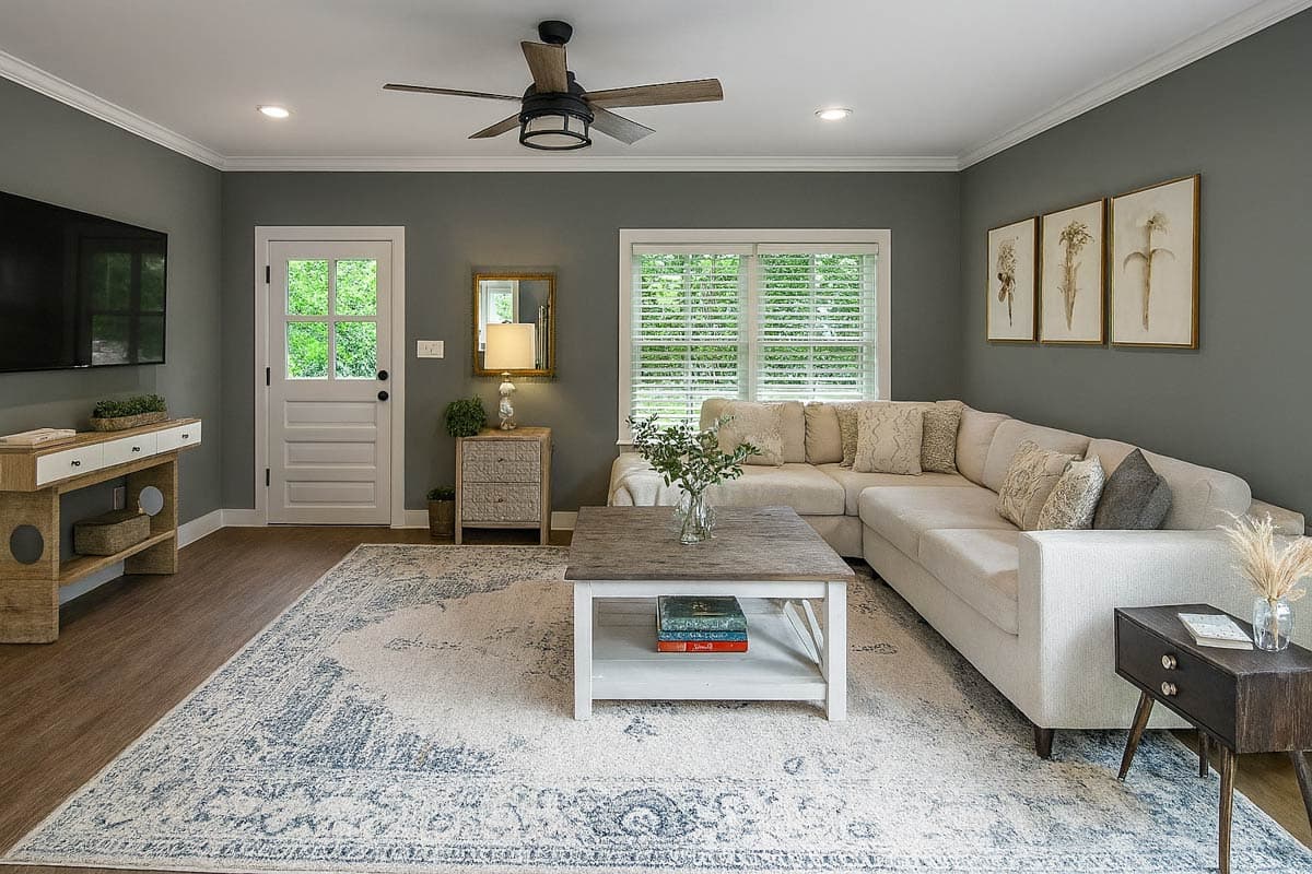 Living room with sectional sofa, coffee table, patterned rug, and framed botanical art.