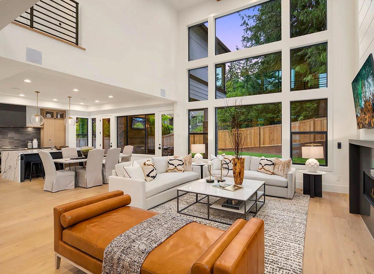 Open-concept living area with vaulted ceilings, large windows, a kitchen with island, and dining area.