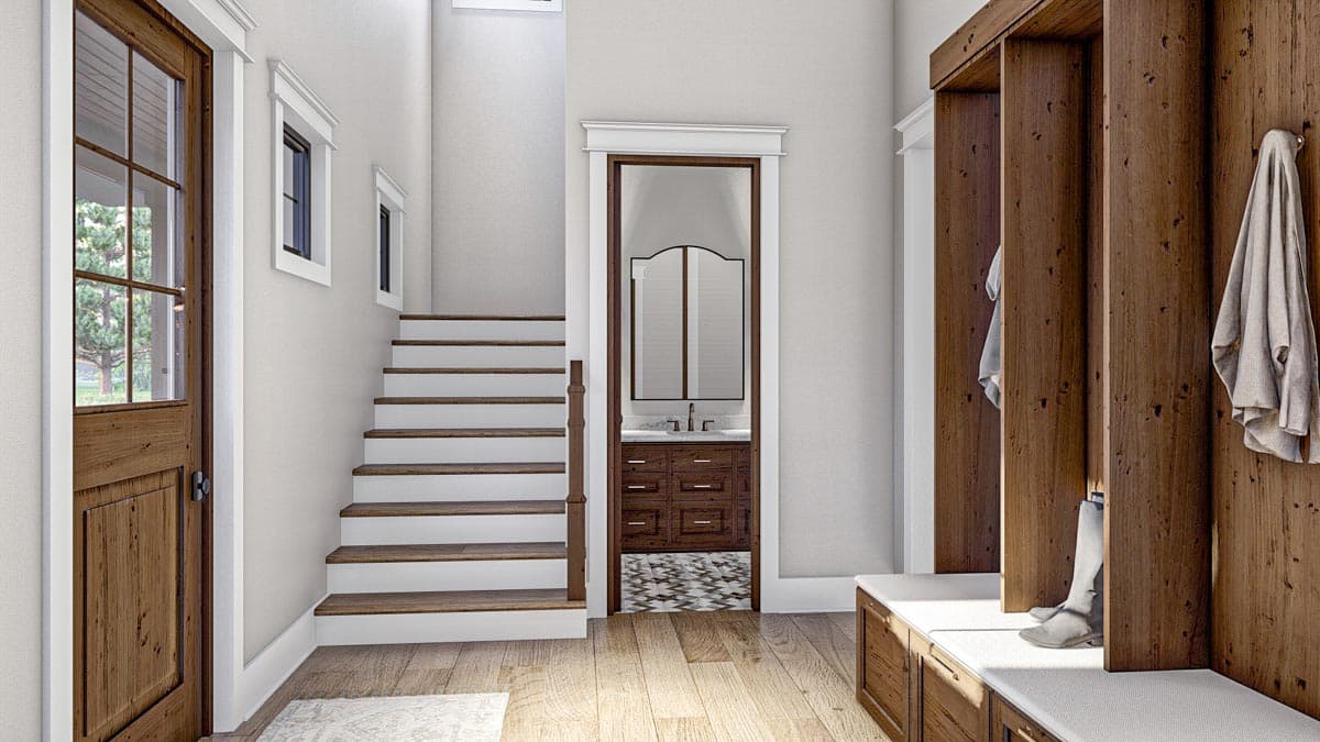Interior view of entryway with wood door, staircase, built-in wood lockers, and doorway to a bathroom with vanity.