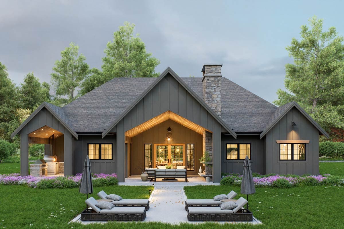 Modern Farmhouse house plan exterior with deep gables, stone chimney, covered porch with outdoor kitchen and lounge area.