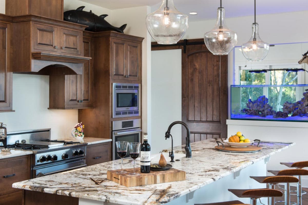 Kitchen with wood cabinetry, granite island, stainless steel appliances, barn door, and aquarium.