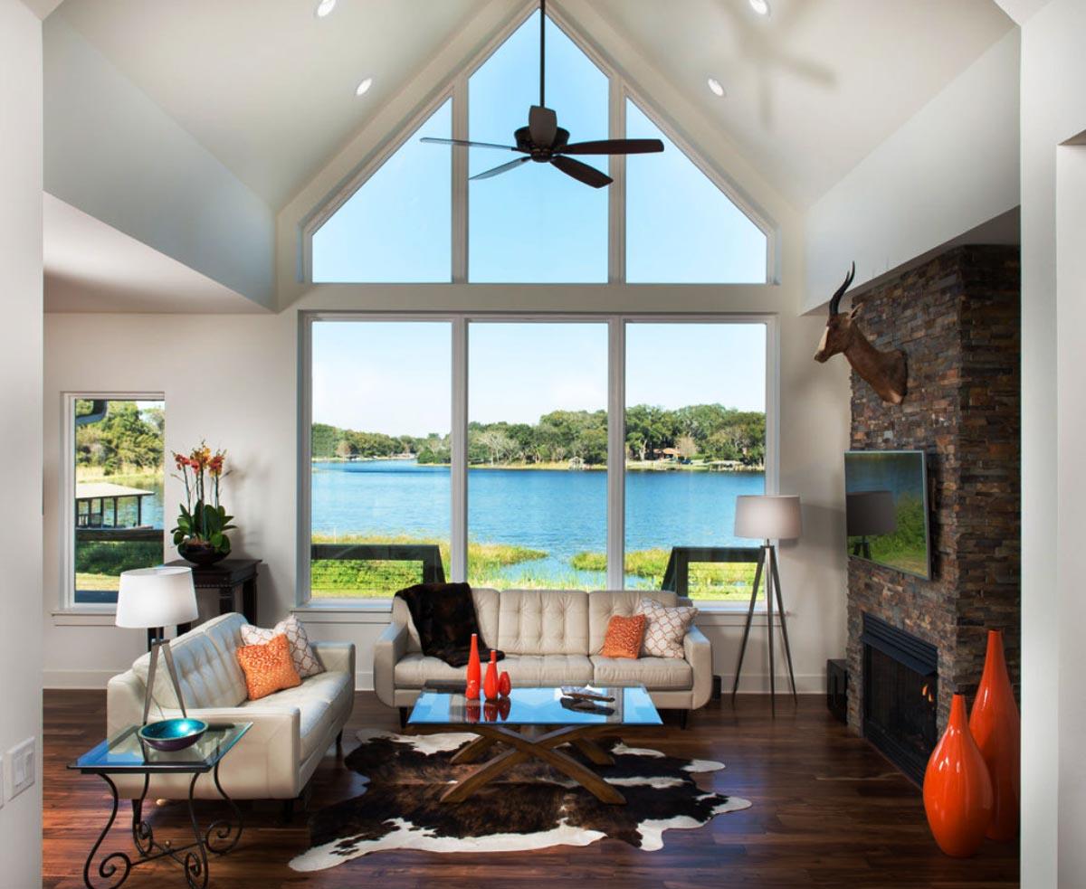 Living room with vaulted ceiling, large window overlooking lake, and stone fireplace.