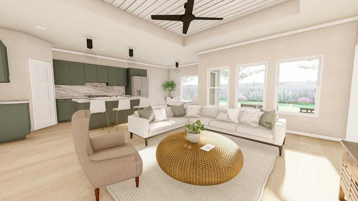 Open-concept living area with a kitchen island, sectional sofa, and large windows. Coffered ceiling with fan.