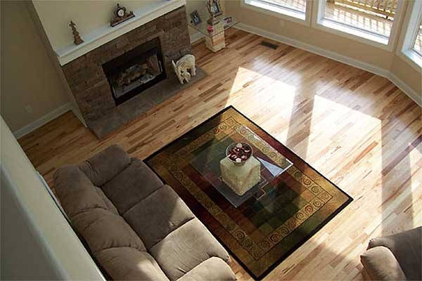 Living room with stone fireplace, large windows, hardwood floors, and sectional sofa.