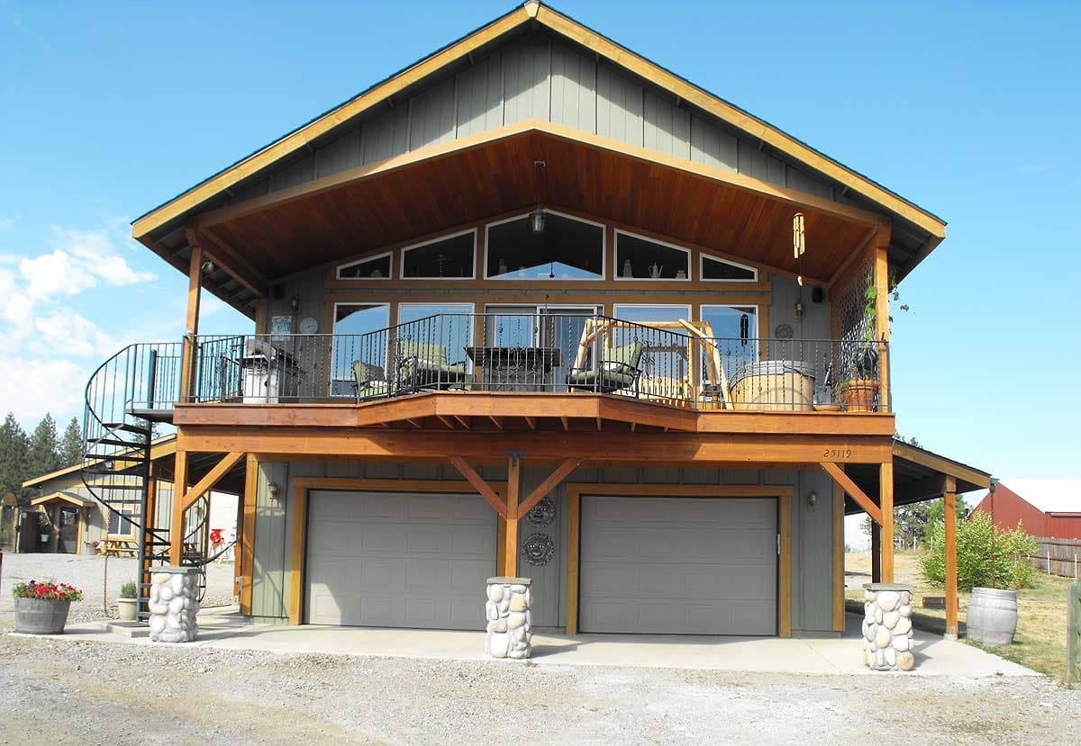 House plan exterior: Two-story home with two-car garage, upper-level deck, and spiral staircase.