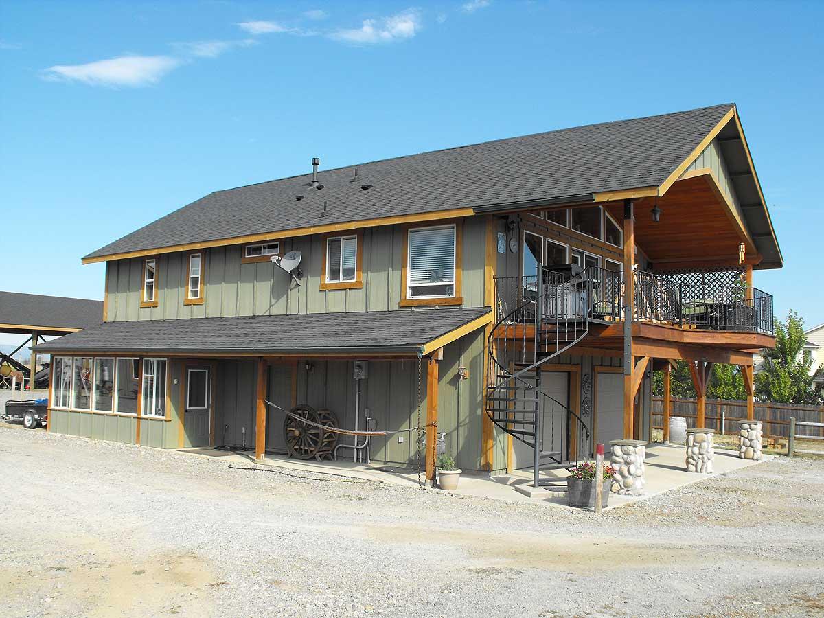 Two-story house plan exterior with a covered porch, sunroom, upper deck with spiral stairs, and gabled dormers.