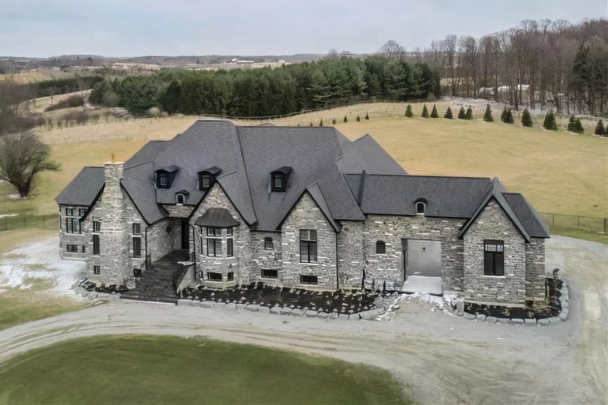 Stone house plan exterior with multiple gables, dormers, a bay window, and an attached garage.