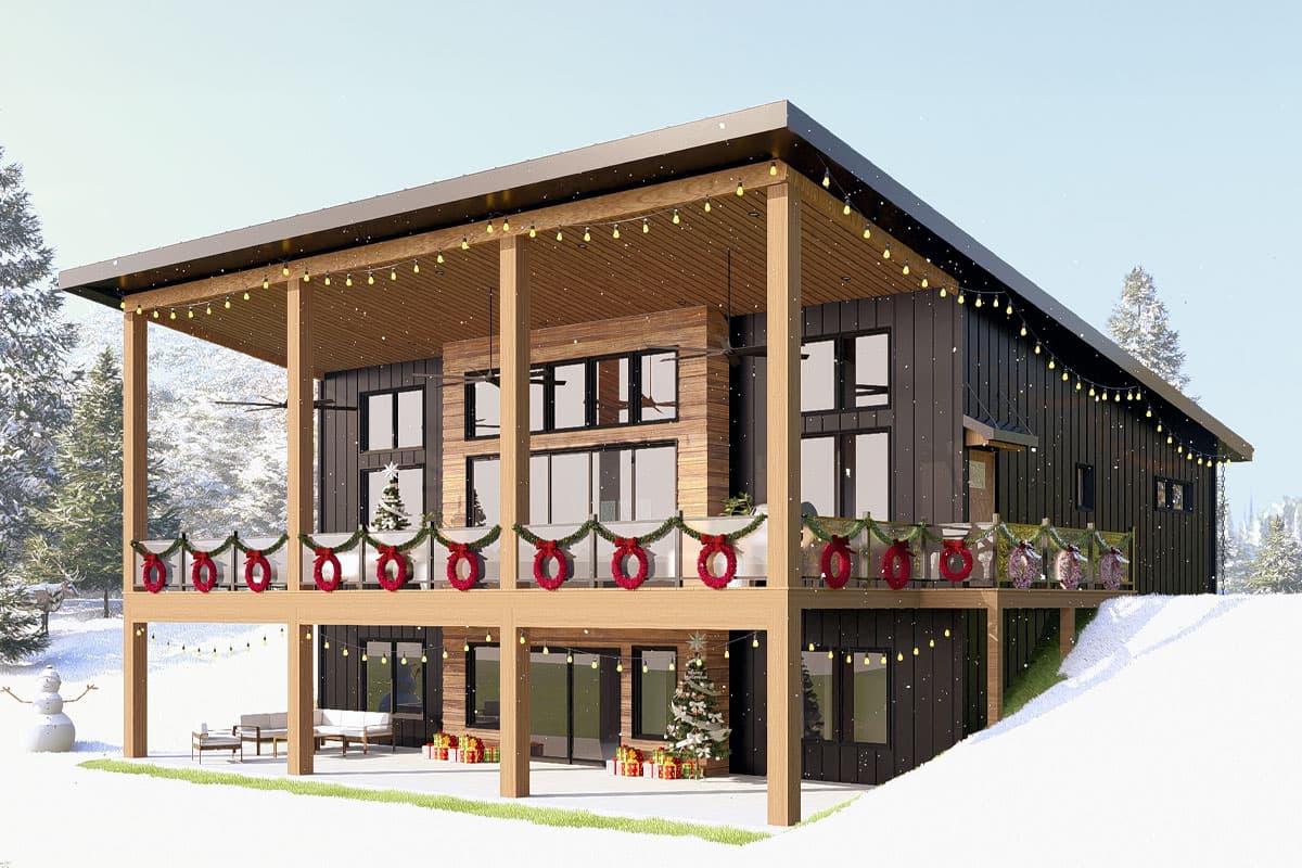 A modern two-story house with Christmas decorations, wreaths, and string lights, surrounded by a snowy landscape, a snowman, and a small Christmas tree.