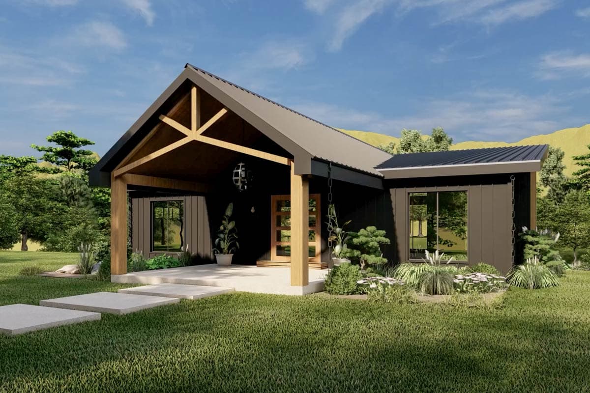 A modern, dark-colored house with a covered porch and wooden beams. Landscaping includes green grass and small trees against a blue sky.