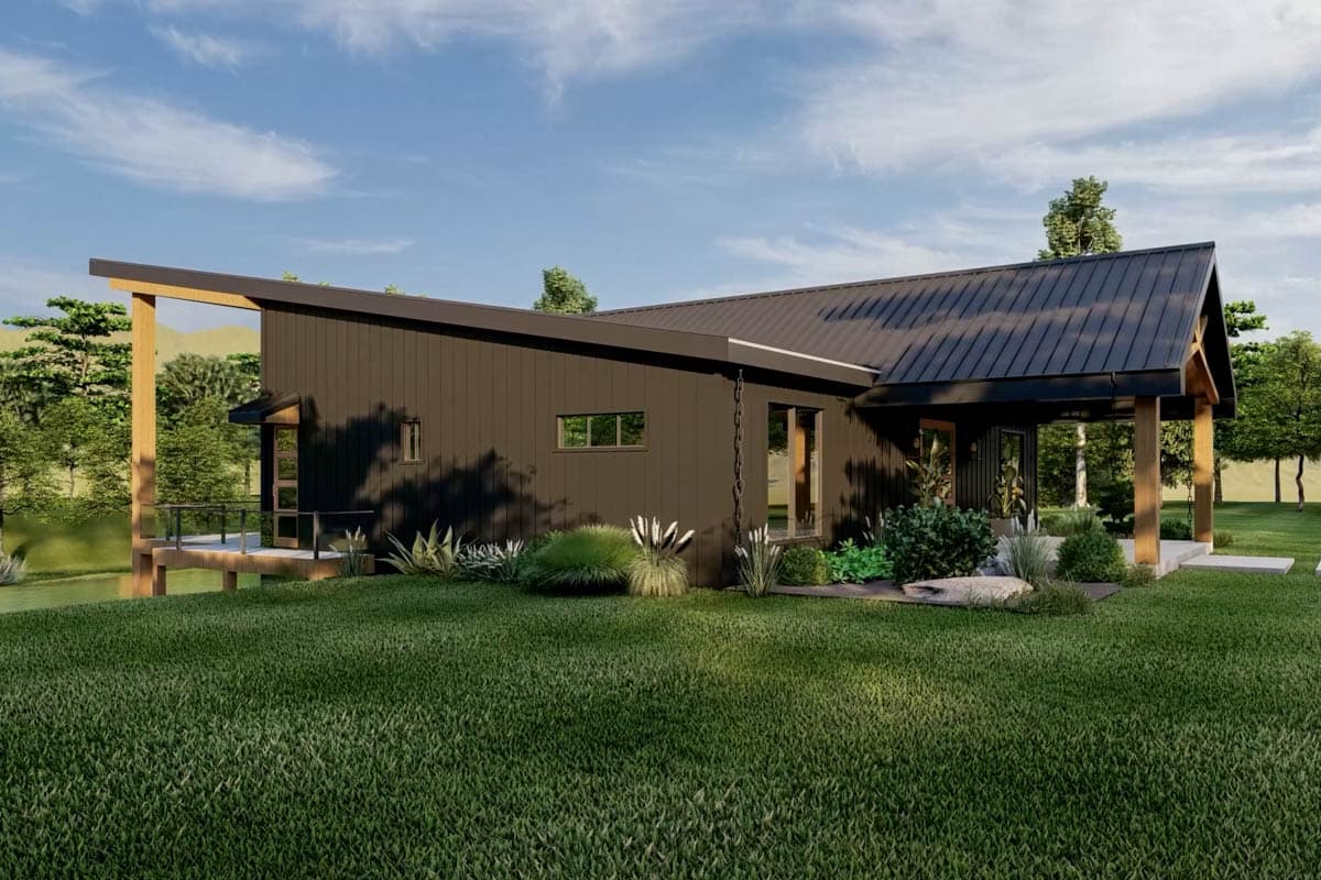 A modern, dark-colored house with a sloped roof and wooden supports. Lush green grass and landscaping surround the exterior of the home.