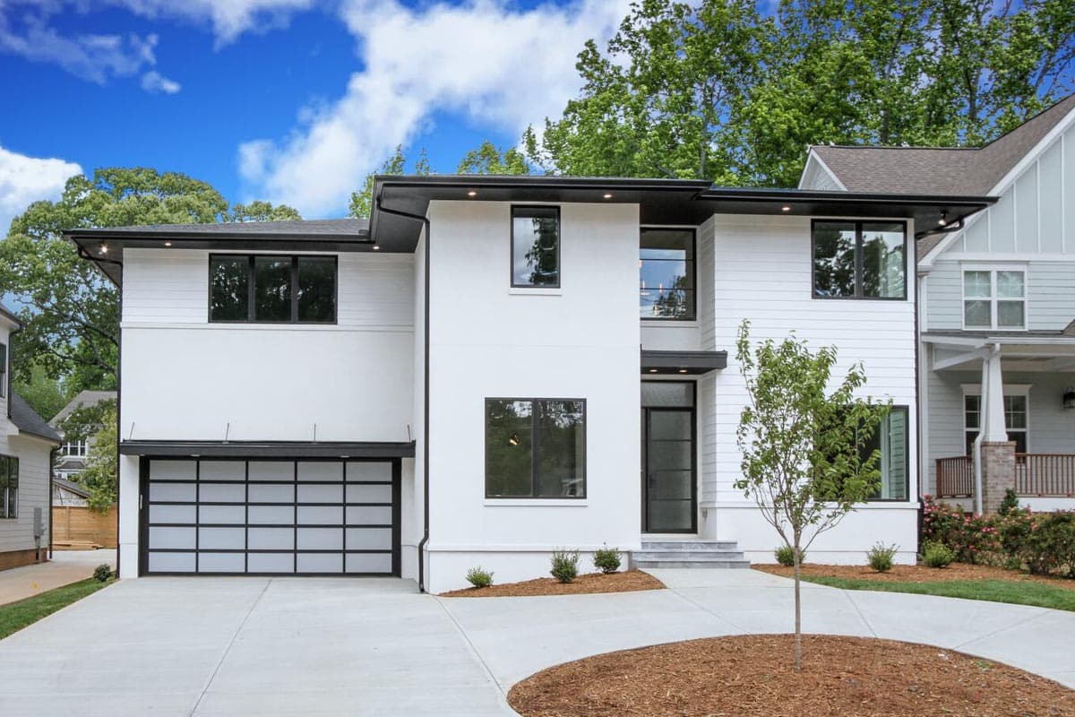 House plan exterior featuring Modern style. Two-story home with a glass garage door, black trim, and flat rooflines.