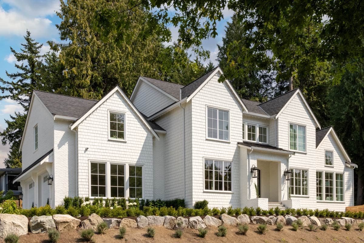 House plan exterior. Two-story, shingle-sided house with multiple gables, a front entry porch, and a side-entry garage.