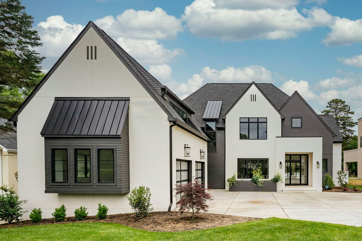 Modern house plan exterior with multiple gables, standing seam metal roof accents, bay window, and two-car garage with glass doors.