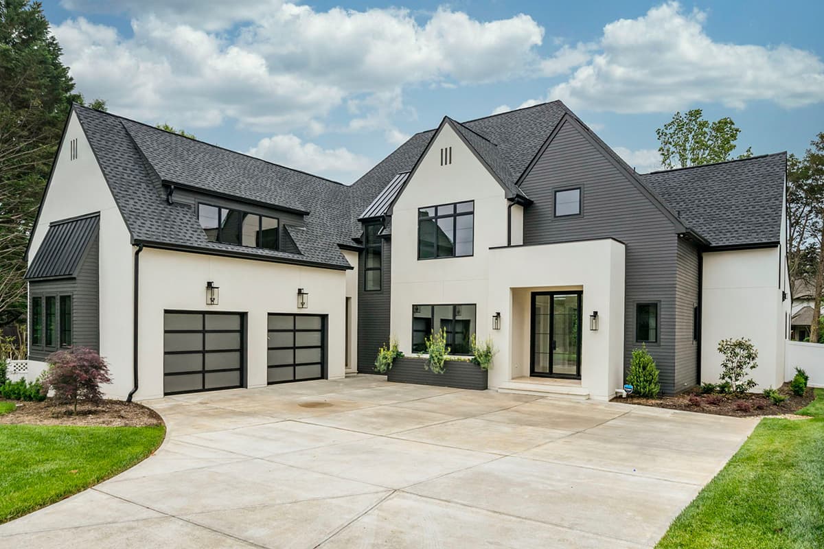 Modern house plan exterior with stucco and dark siding, a prominent gable, and a three-car garage with glass doors.