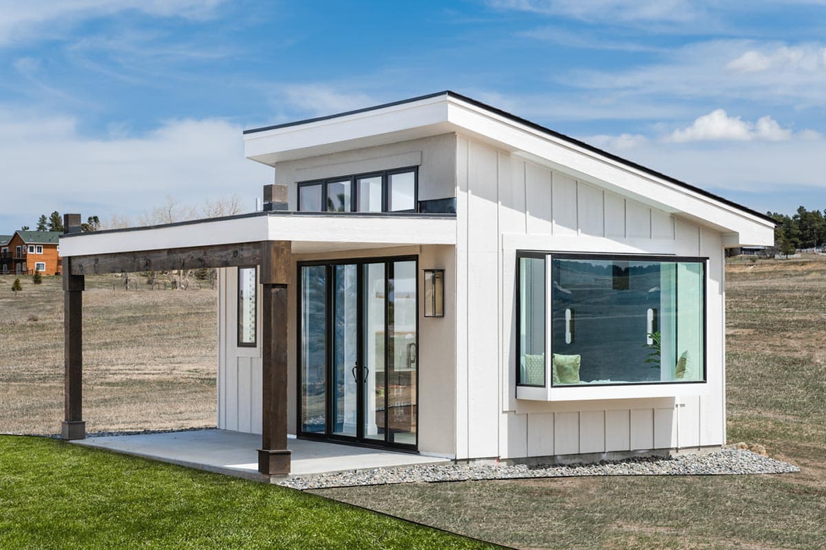 Modern house plan exterior with board and batten siding, covered patio, and large bay window.