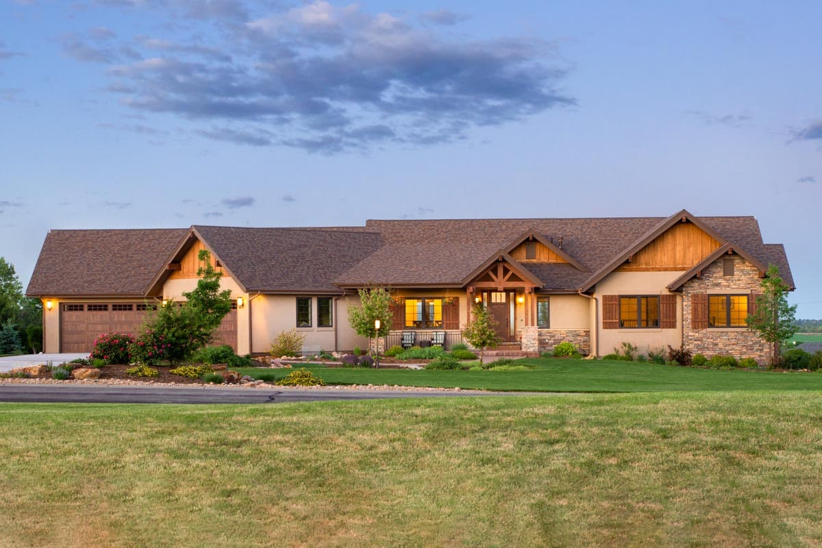 House plan exterior. Ranch-style home with a single story, multiple gables, a front porch, and an attached, three-car garage. Stone and wood accents.