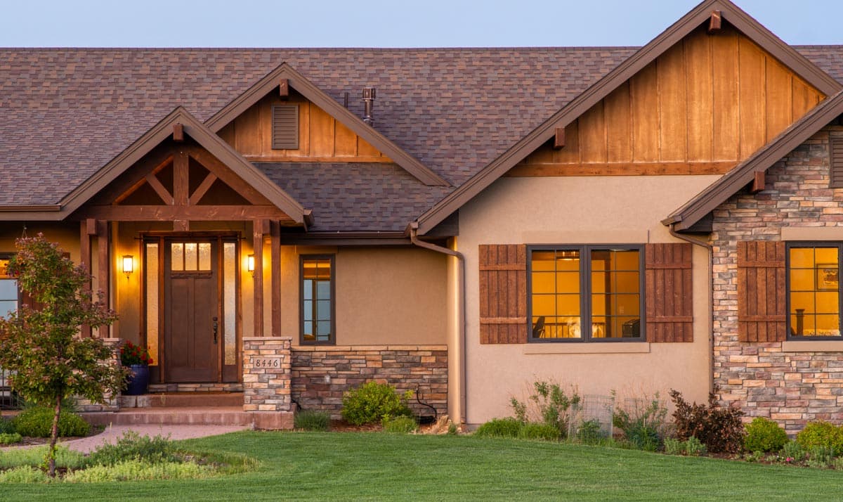 Craftsman house plan exterior with covered entry, stone accents, gabled rooflines, and wooden shutters.