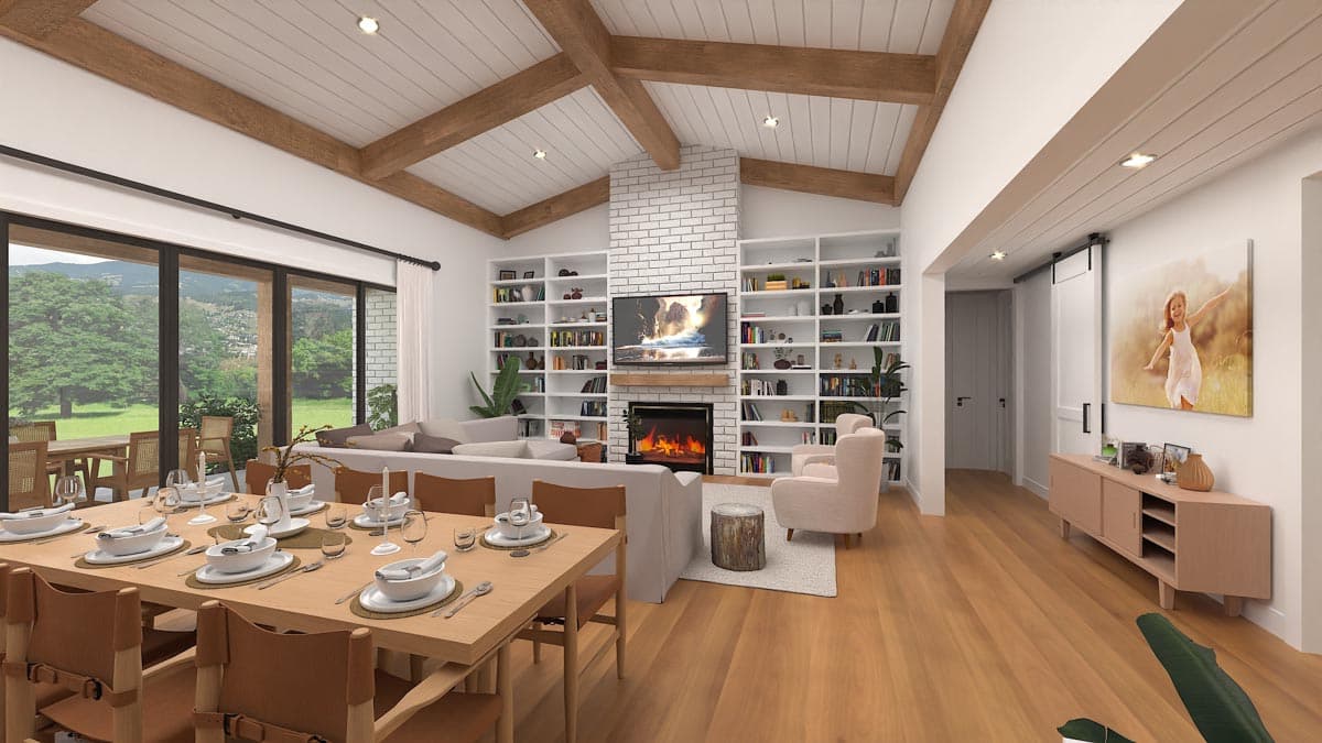 Dining and living area with vaulted beamed ceiling, fireplace, built-in bookshelves, and large windows overlooking a lawn.