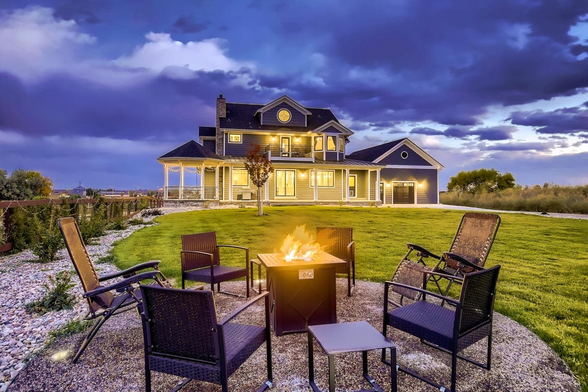 House plan exterior: two-story Modern Farmhouse with wrap-around porch, circular dormer, and attached garage.