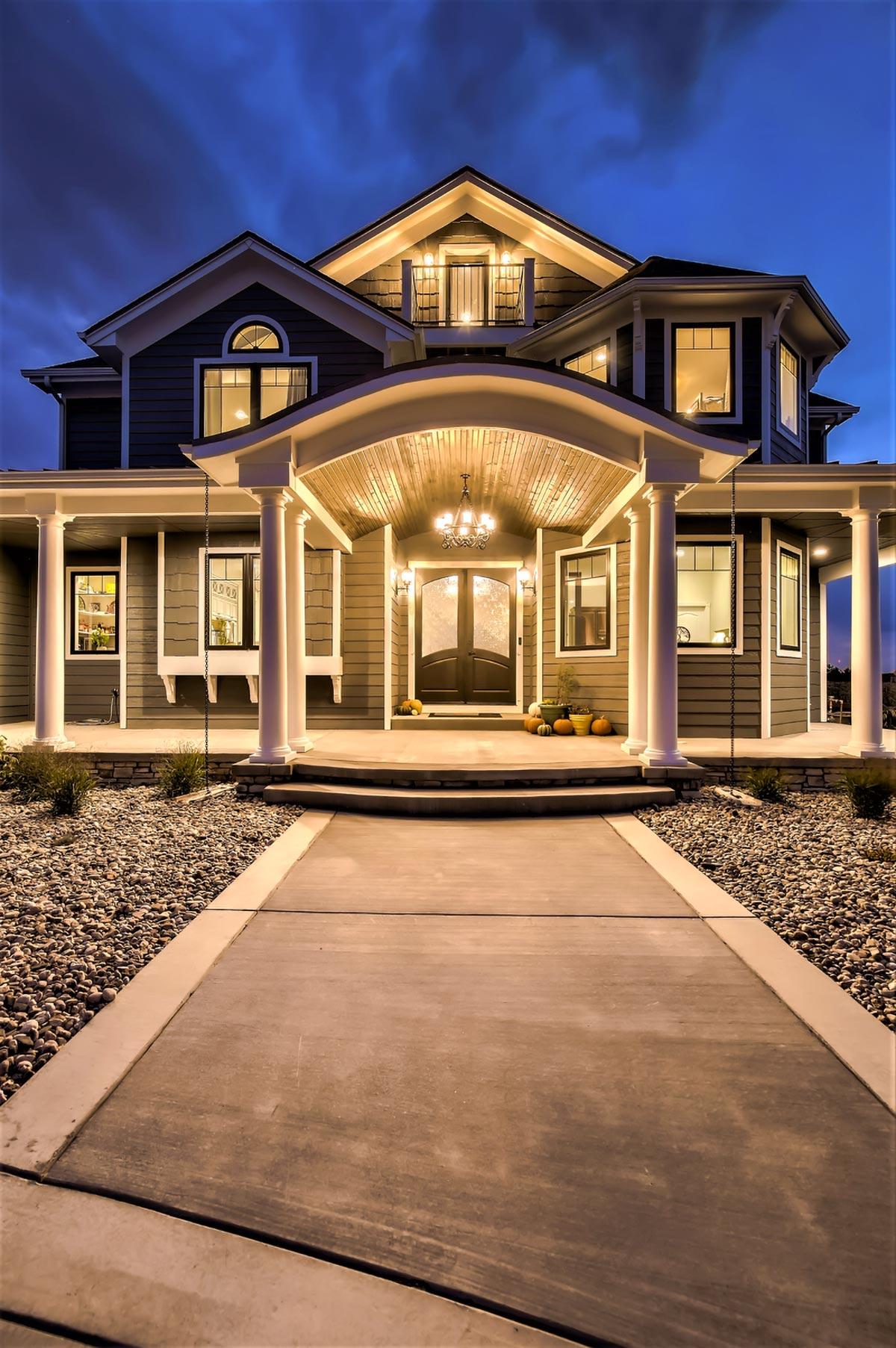 House plan exterior: Covered porch with columns, arched entryway, dormers, and multiple gables. Two stories visible.