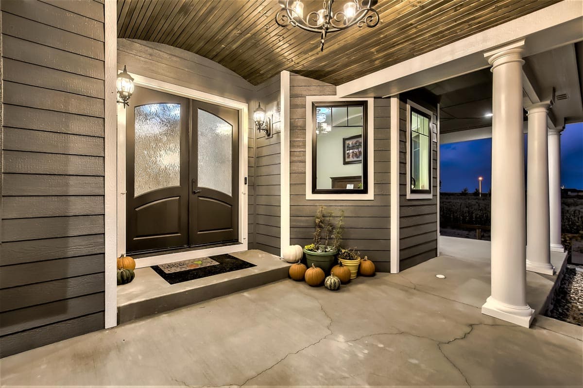 House plan exterior features a covered porch with double arched doors, decorative windows, and classical columns.