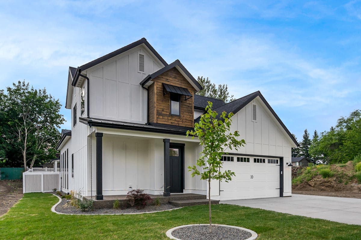 Modern Farmhouse house plan exterior: two stories, white board and batten siding, dark gables, covered porch, and two-car garage.