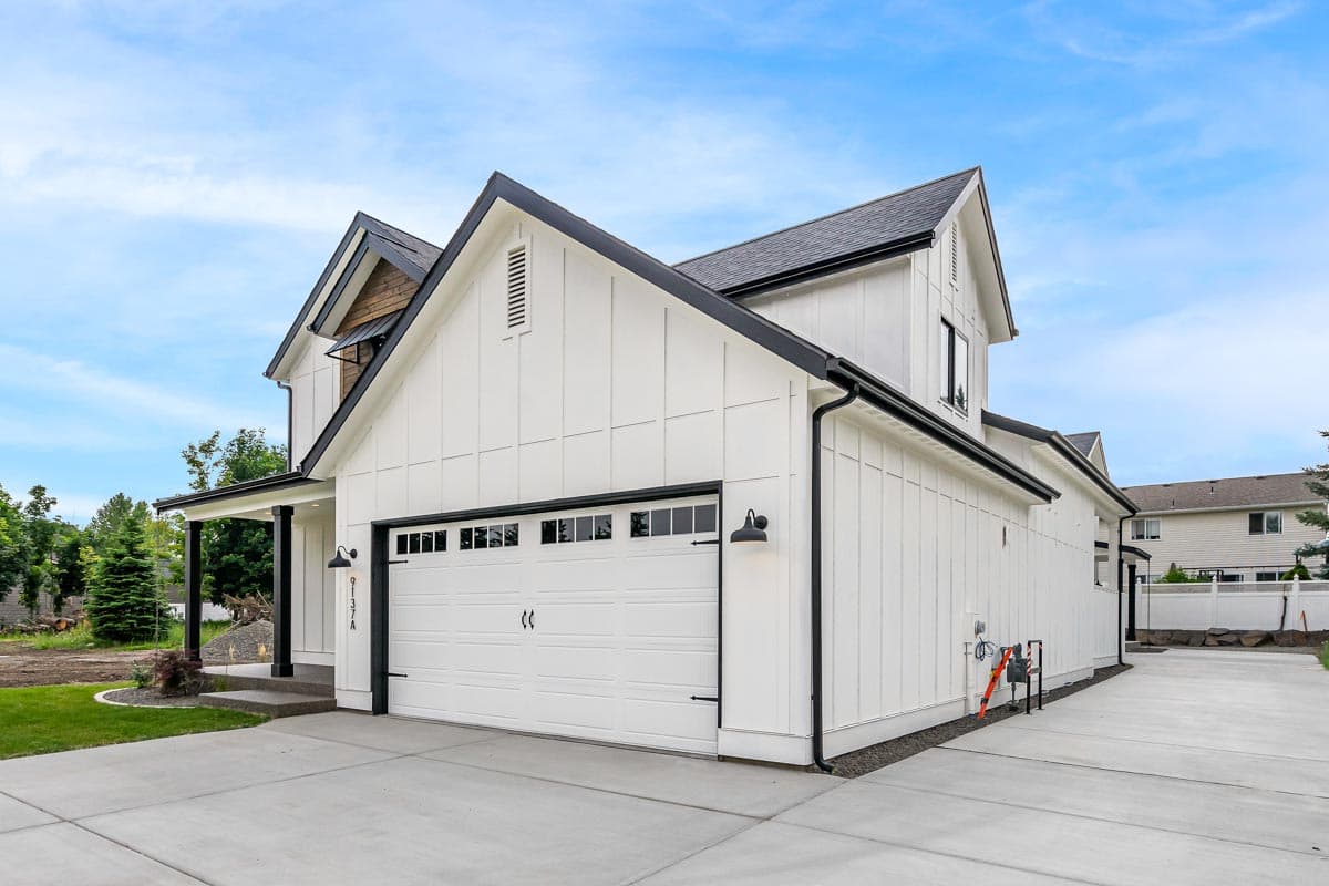 Modern Farmhouse style house plan exterior, two stories, white board and batten siding, gables, and two-car garage.