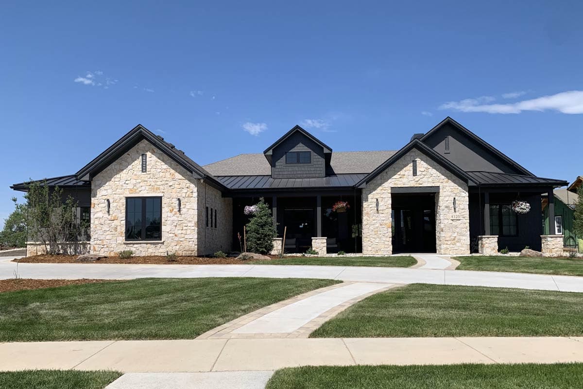 Modern Farmhouse house plan exterior with stone accents, metal roof, multiple gables, and a covered entry.