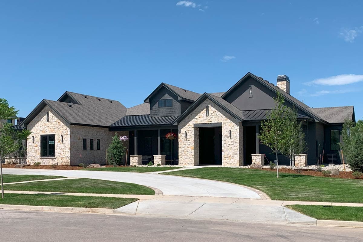 House plan exterior: Modern style, one-story, stone and dark siding, gabled roof, prominent chimney, and attached garage.