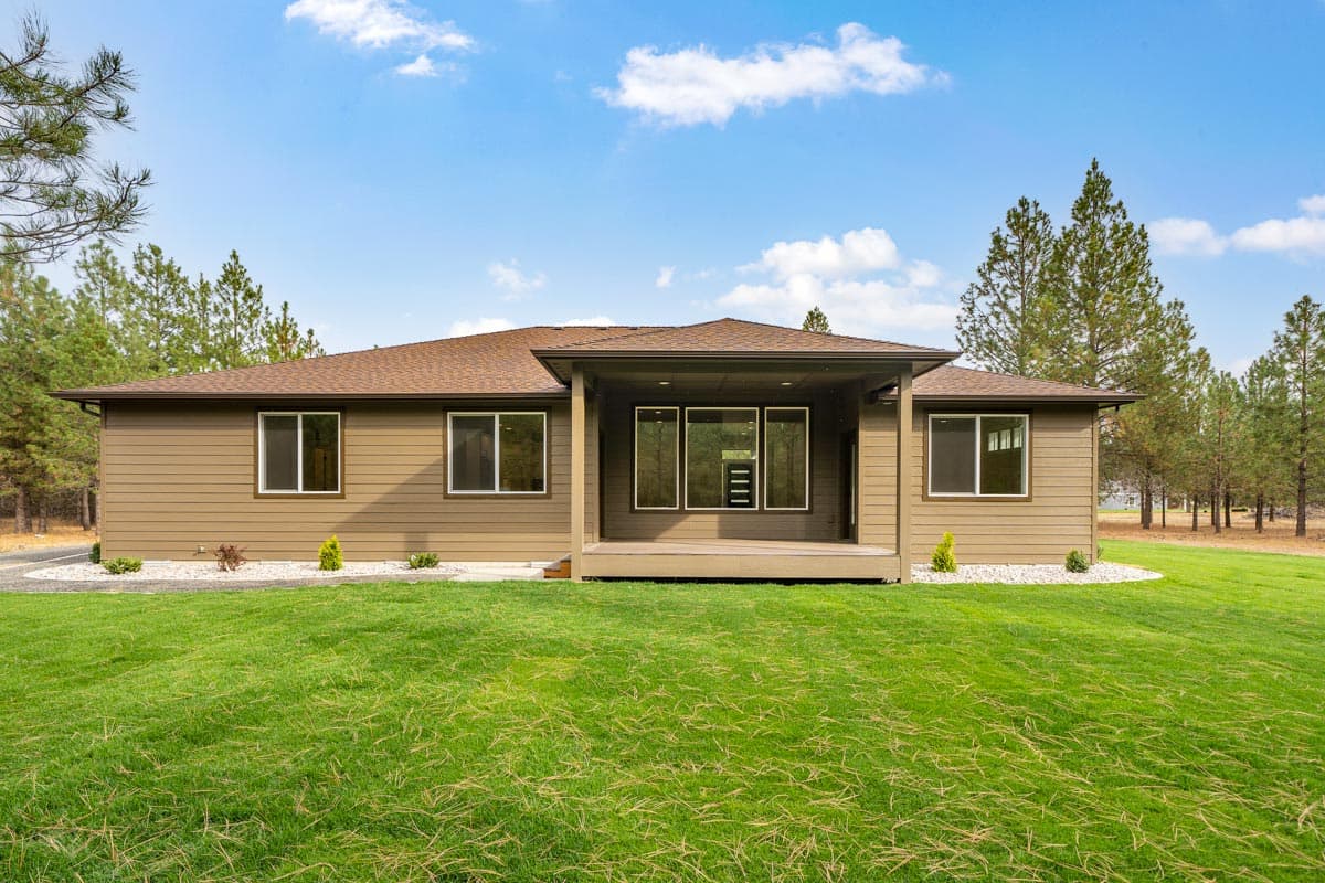 Ranch house plan exterior with a covered deck, large windows, and hip roof.