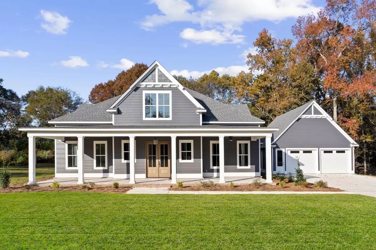 House plan exterior. Two-story, farmhouse-style home with a front porch supported by columns, gables, and a detached garage.