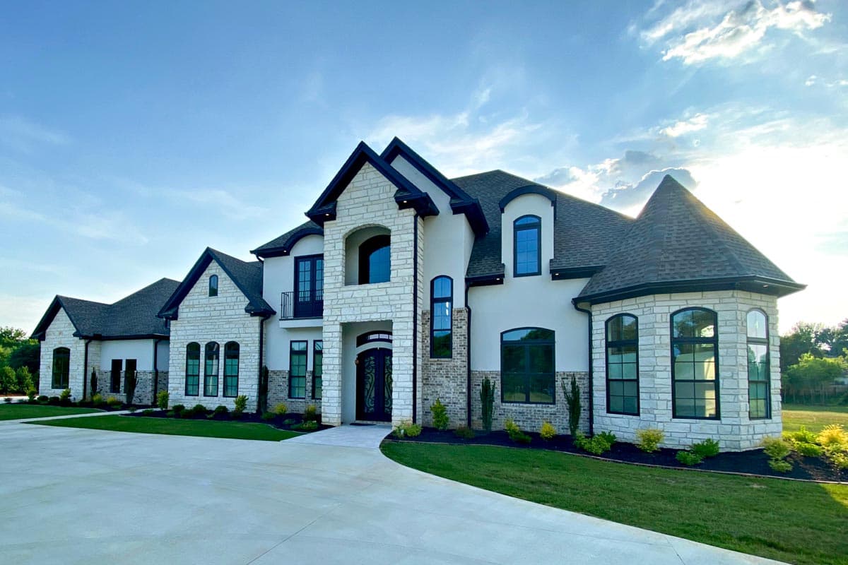 Exterior view of a multi-story house with stone accents, arched windows, dormers, and a turret.