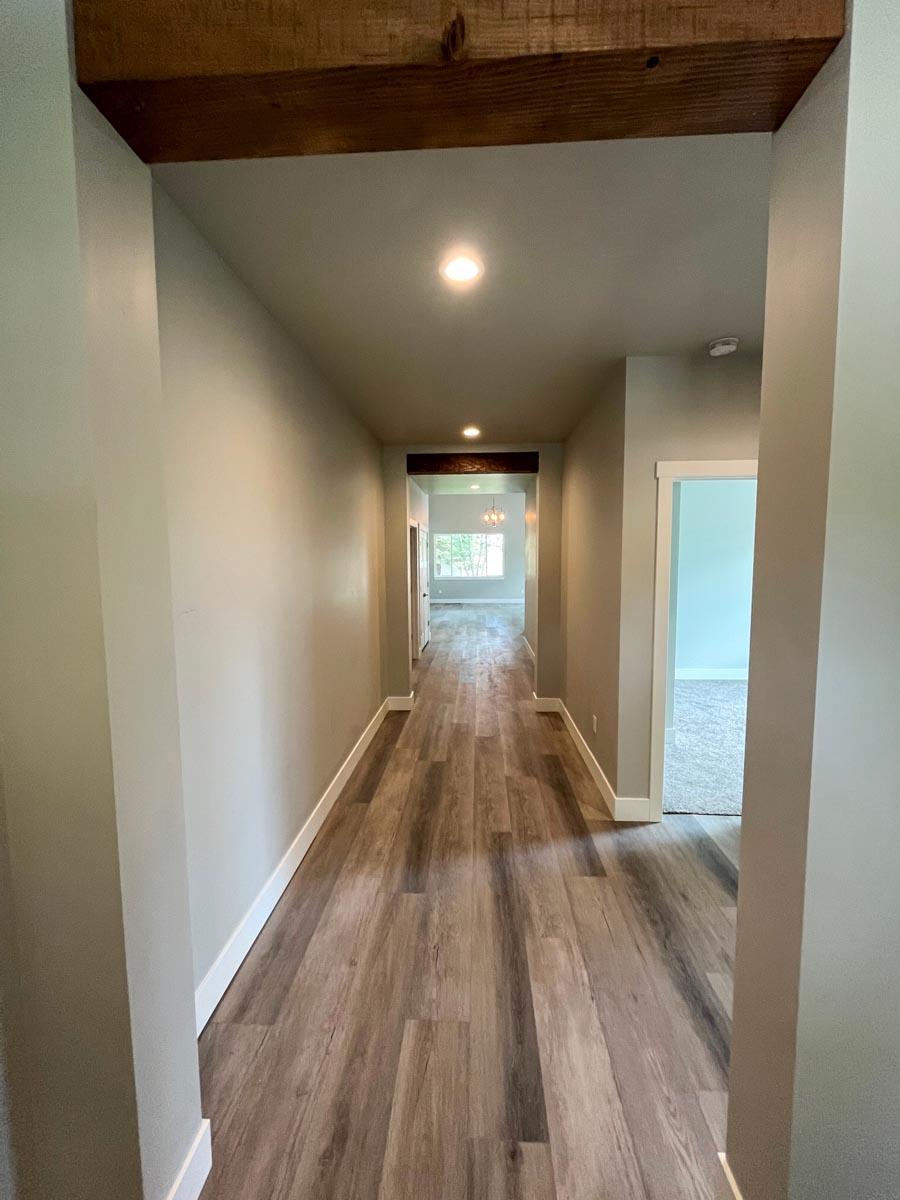 Interior hallway with wood-look flooring, recessed lighting, and a visible wood beam across the ceiling.