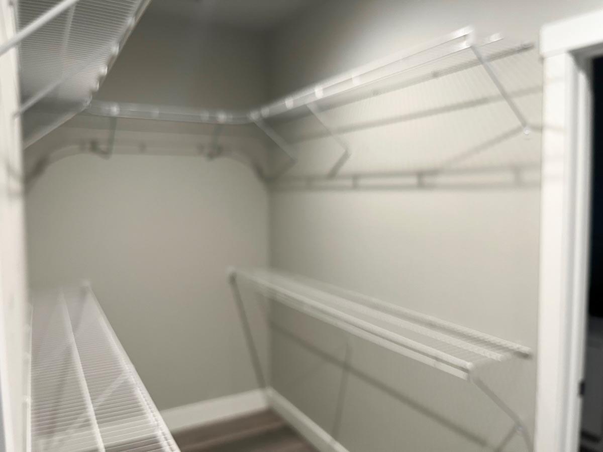 Walk-in closet with corner shelving and a white wire shelving system.