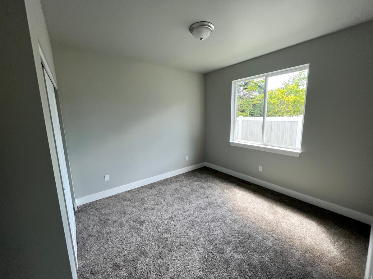 Interior view of an empty bedroom with carpet, a single window, and a ceiling light.