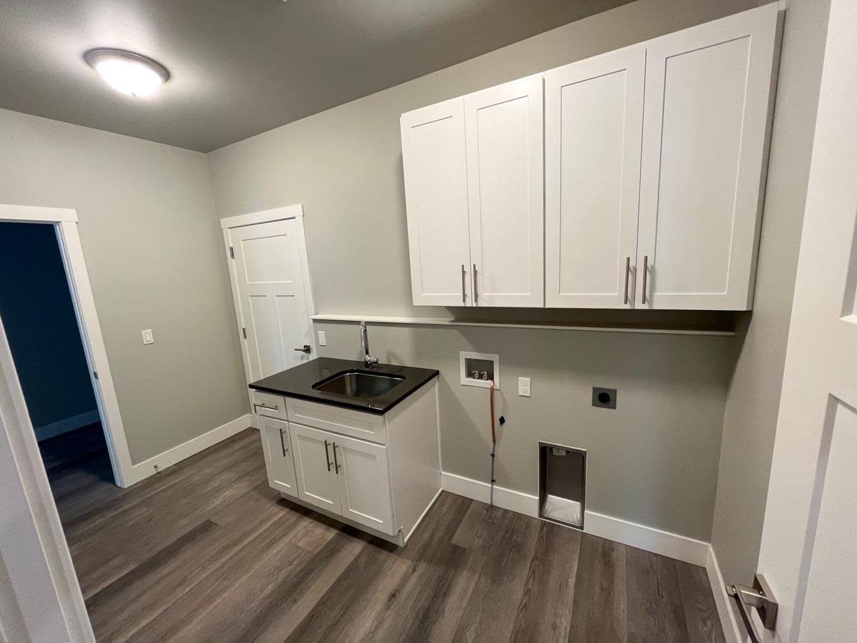 Laundry room with white cabinets, sink, and hookups for washer and dryer.