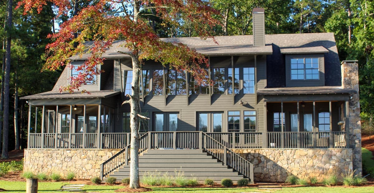 House plan exterior: Two-story Modern Farmhouse with stone foundation, screened porches, extensive decking, and dormer windows.