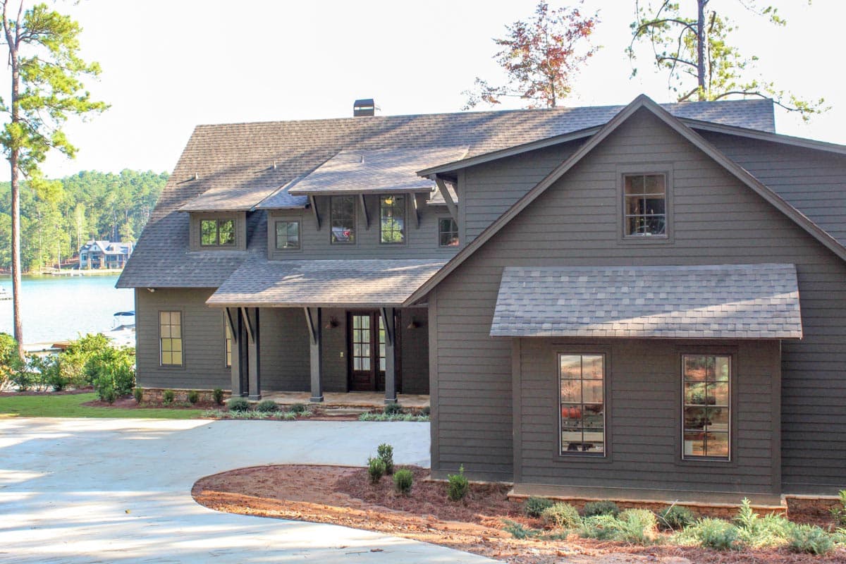 House plan exterior: Two-story modern farmhouse with gabled dormers, a covered porch with decorative supports, and a lake view.