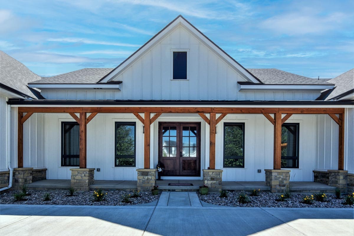 Modern Farmhouse house plan exterior with a covered porch supported by wooden beams and stone-clad columns.