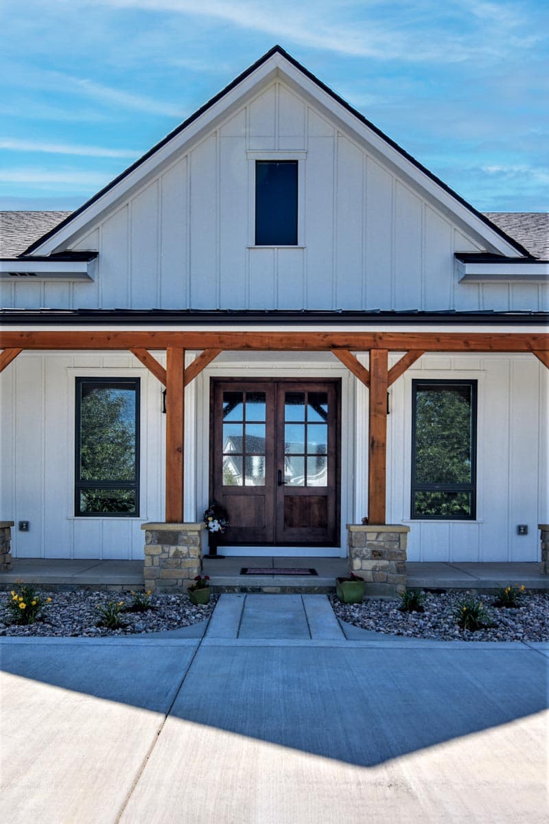 Modern Farmhouse exterior with double front doors, wood beam porch supports, stone accents, and board and batten siding.
