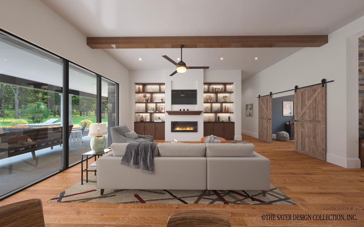 Living room with fireplace, built-in shelving, ceiling fan, and large sliding glass doors overlooking patio.