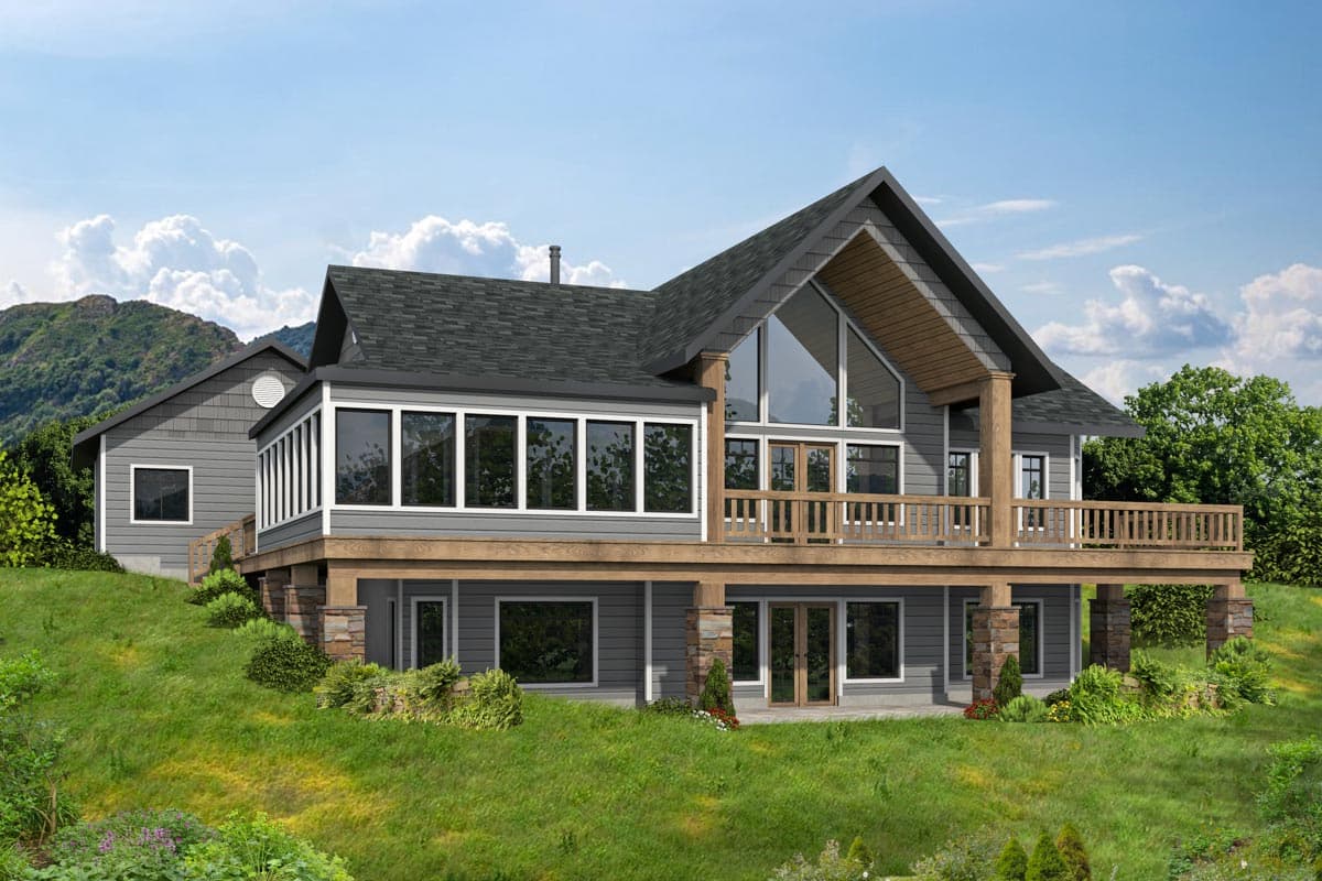 House plan exterior. Two-story home with a gabled roof, large windows, and a wraparound deck. Stone and wood columns support the deck.