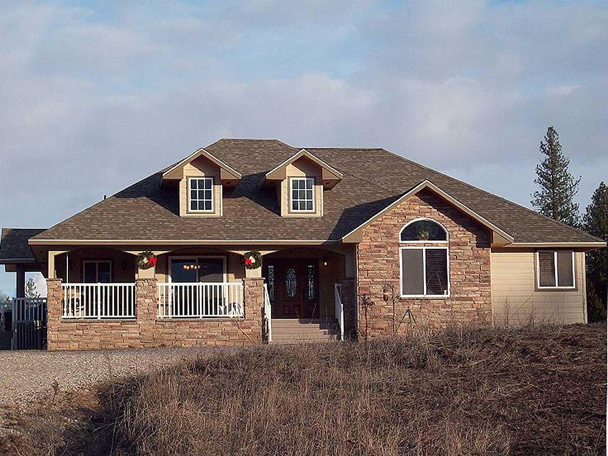 House plan exterior. Ranch style with stone facade and a porch. Features include gable dormers, a covered porch, and a hipped roof.