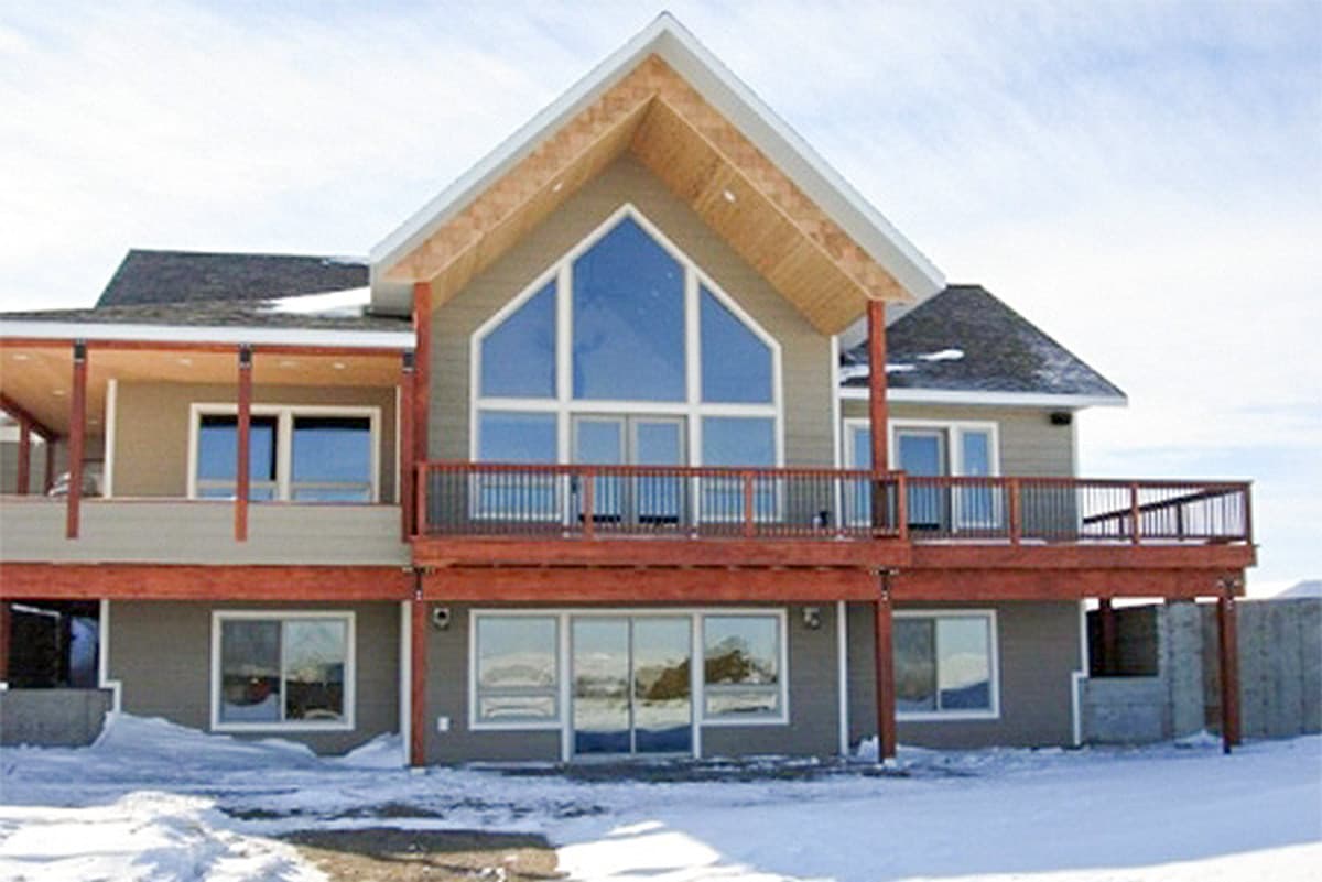 House plan exterior with large gable window, covered porch, and wrap-around deck.