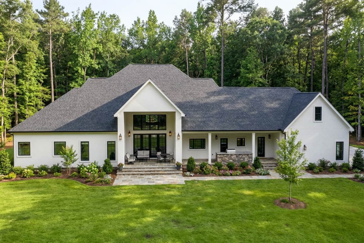 House plan exterior: Modern home with large central gable, dual chimneys, expansive glass doors, and a covered patio area.
