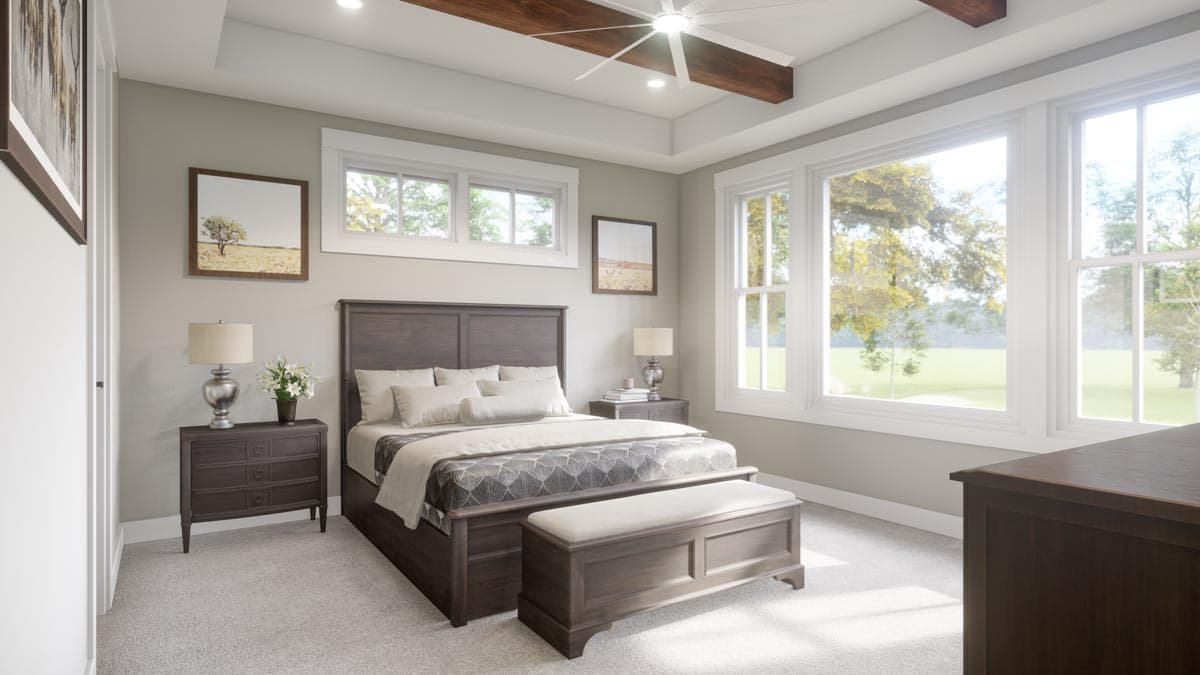 Primary bedroom with tray ceiling, exposed wood beams, large windows, and upholstered bench at foot of bed.